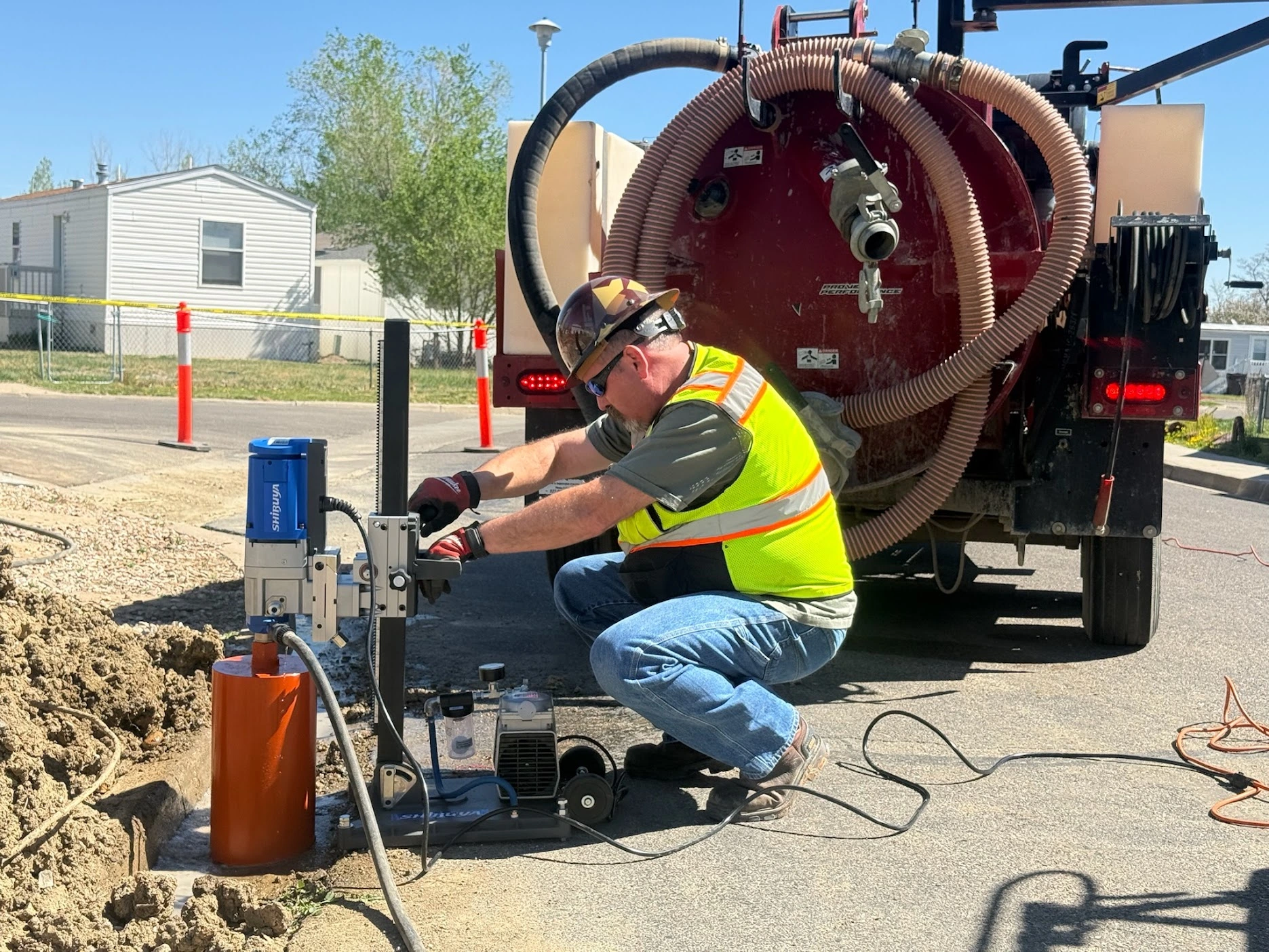 OnGrade technician core drilling a street next to a hydro-excavation vacuum truck