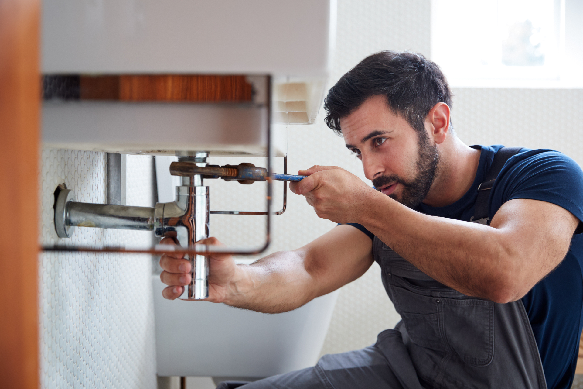 Plumber repairing a sink drain with a wrench